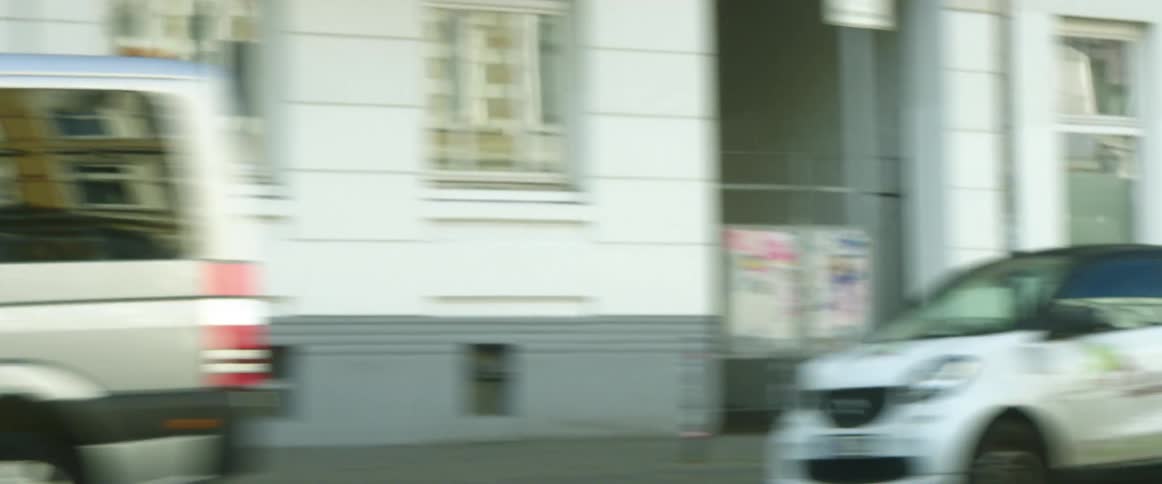 Multiple cars are driving on a street in an urban city