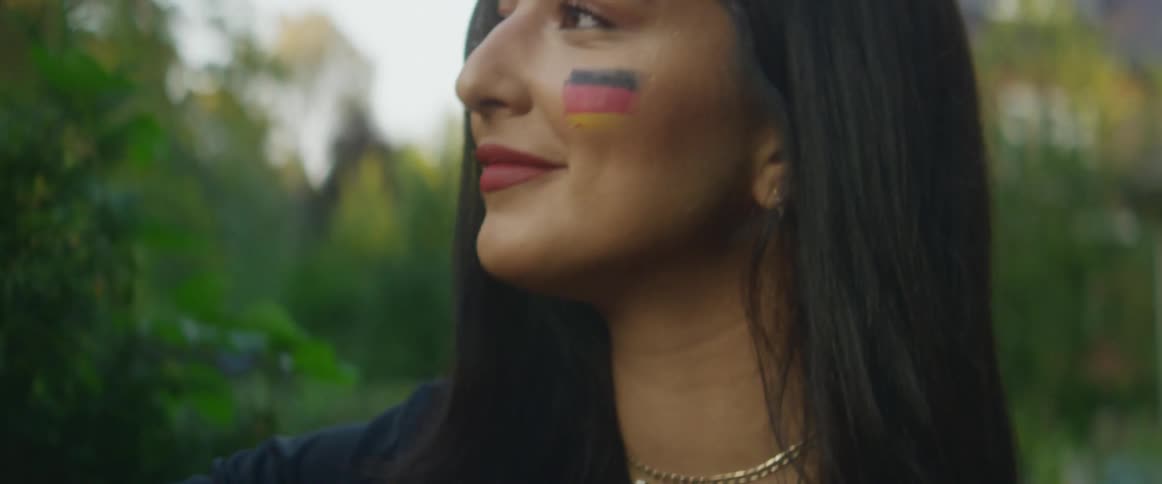 A woman smiles as she applies matching face paint to a mans face