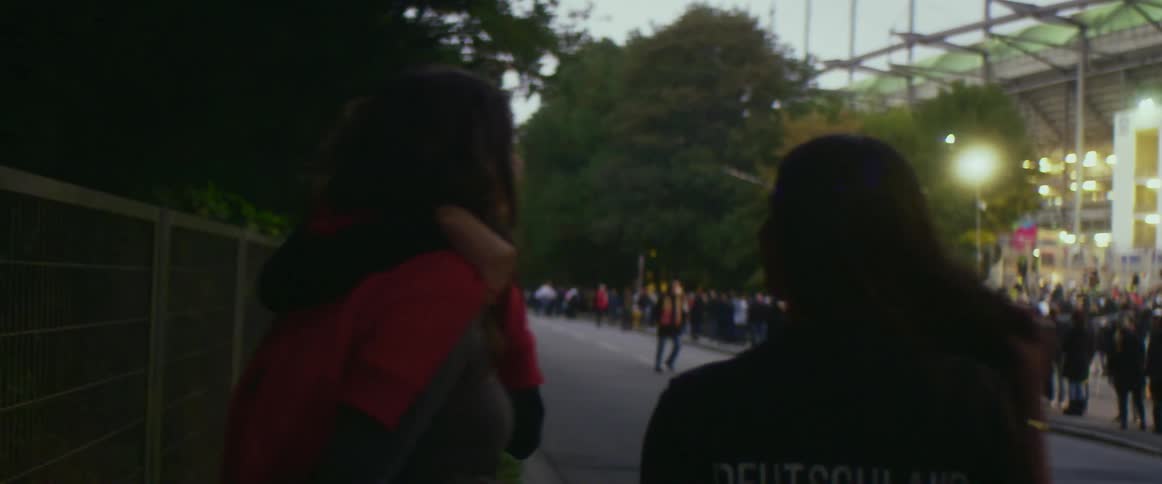 People are standing outside of a stadium at dusk