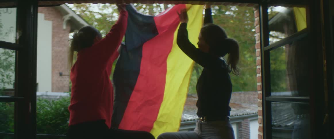Two women are putting up a flag together
