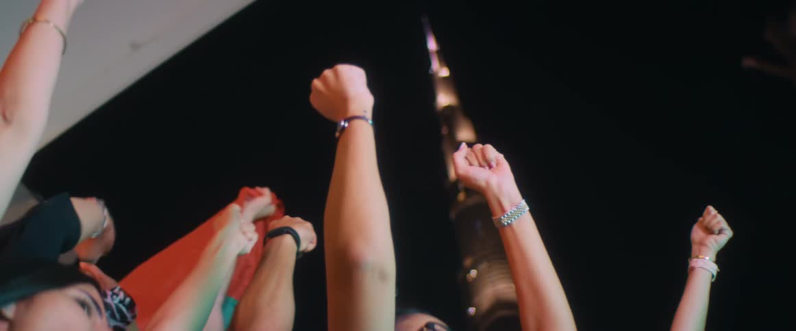 A crowd raises their arms into the air and cheers at an event