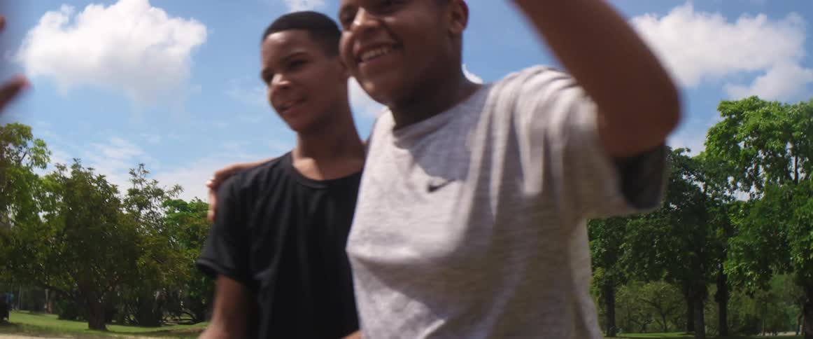 A group of young males congratulate each other outside on a sport field