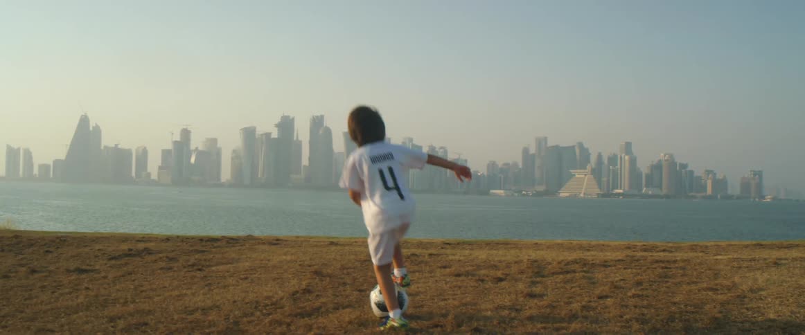 A boy is playing soccer on the coast of a beach