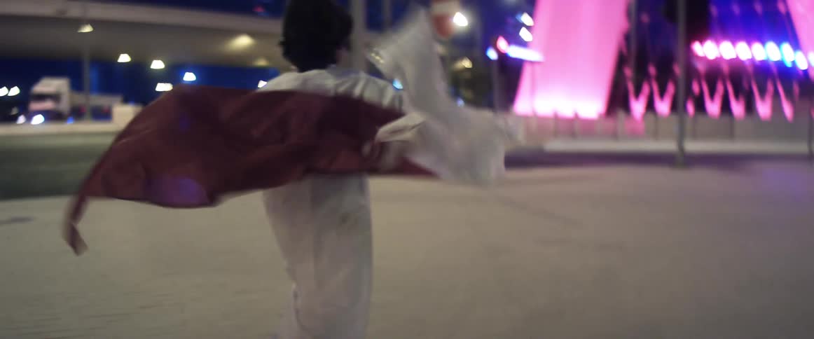 A boy carries a flag behind him as he runs around a plaza near downtown