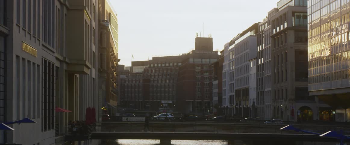 A pedestrian crossing a canal bridge surrounded by city buildings