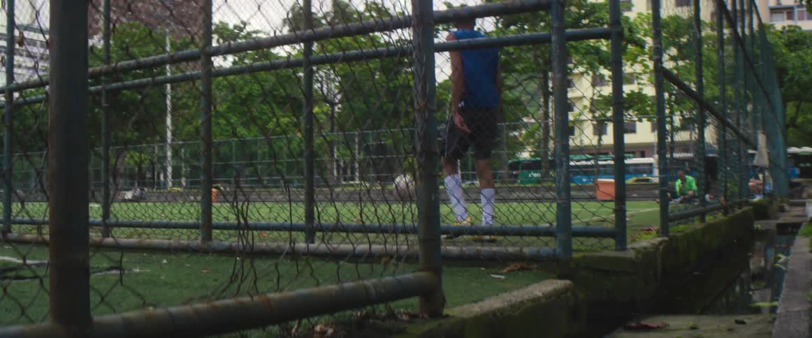 A man drops a soccer ball onto an outdoor soccer field and jogs after it