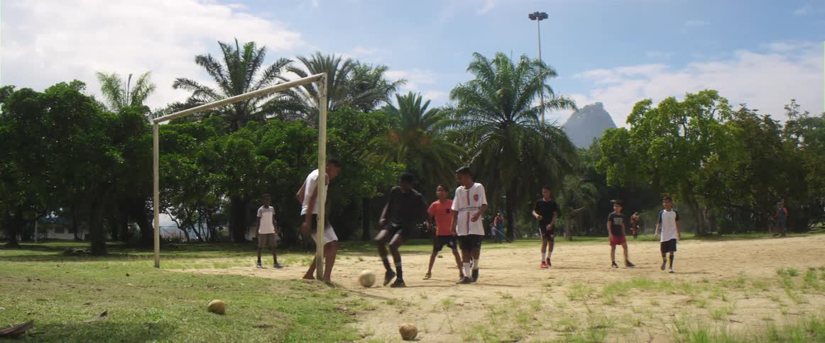 A group of boys kick a soccer ball in to the goal during a game
