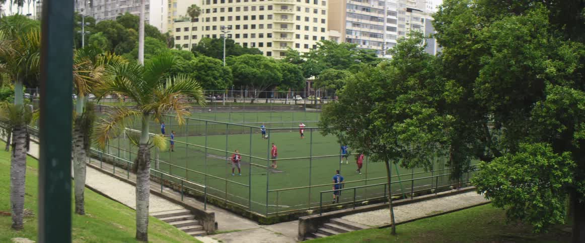 Men wearing blue and red uniforms play football in astro pitch