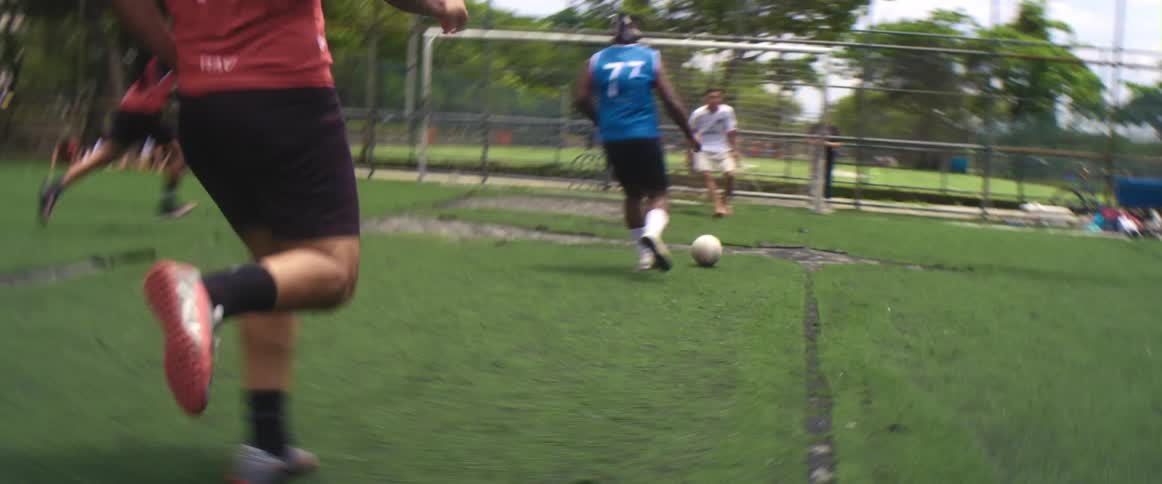 A man runs as he kicks a soccer ball into the goalie net