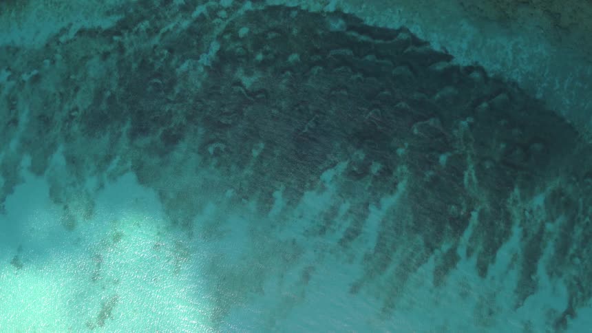 An aerial view of an ocean reef surrounded by turquoise water