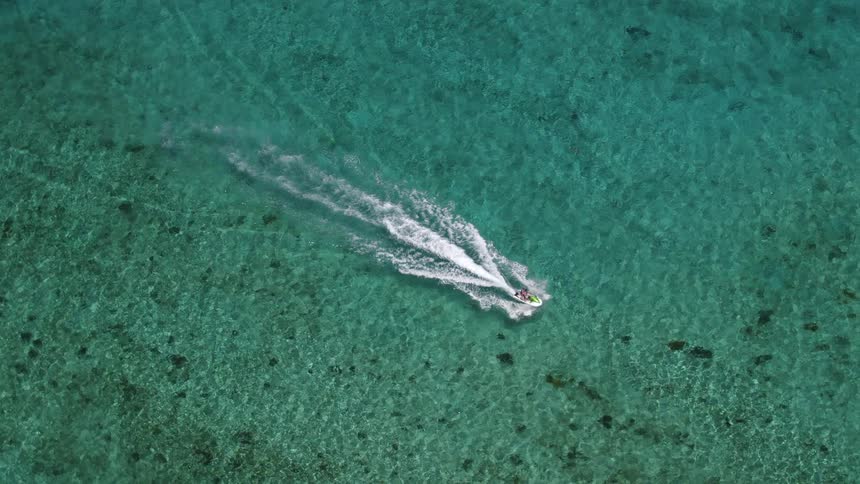 An aerial view of a boat floating on turquoise ocean water in the daytime