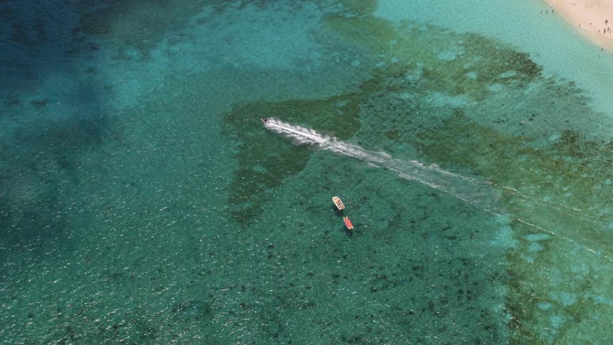 People are jet skiing off the coast of a body of water