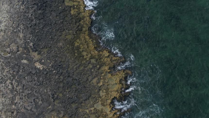 Aerial view of ocean water moving towards the coast is displayed