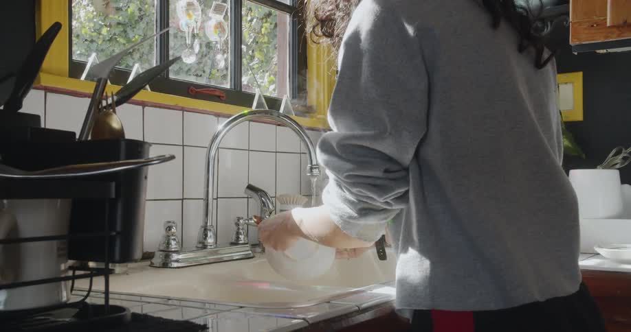A woman is doing dishes in her kitchen