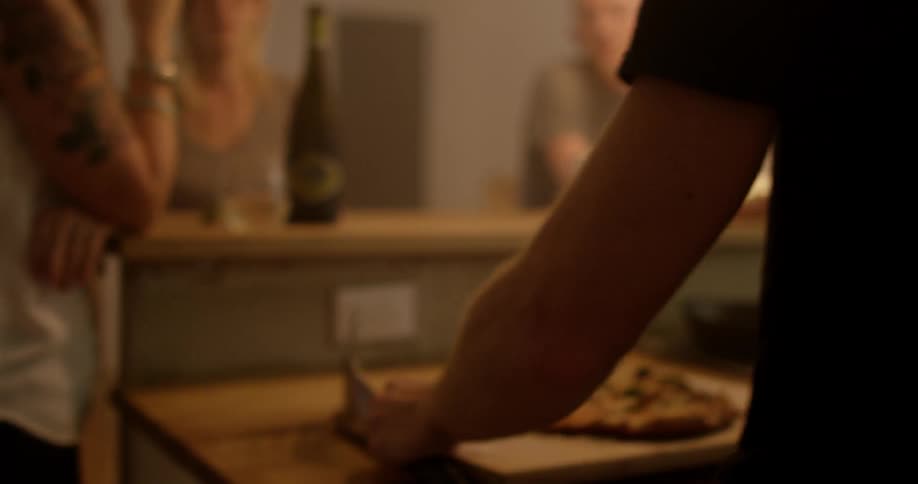 Man bringing out a pizza to a group of people