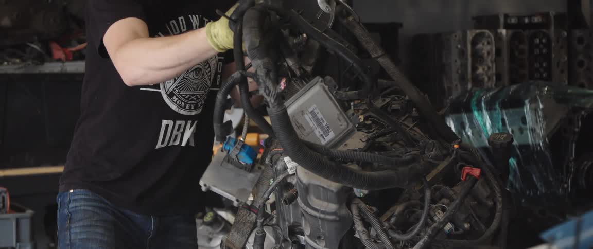 A mechanic moving wires off of an engine