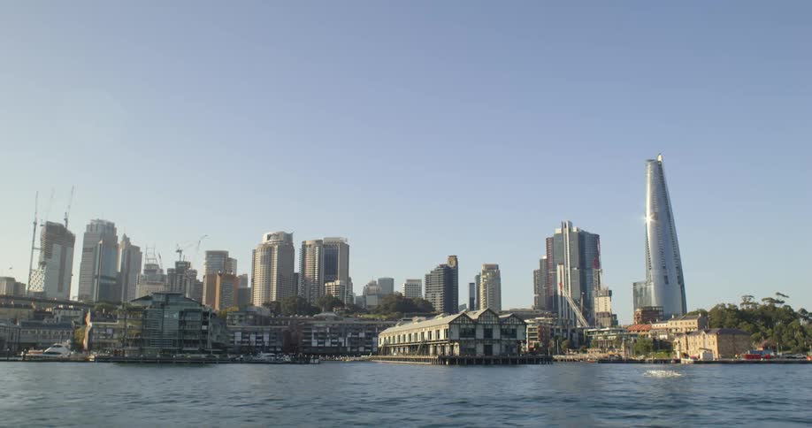 Tall skyscrapers in the city skyline filmed from a boat on a river at morning