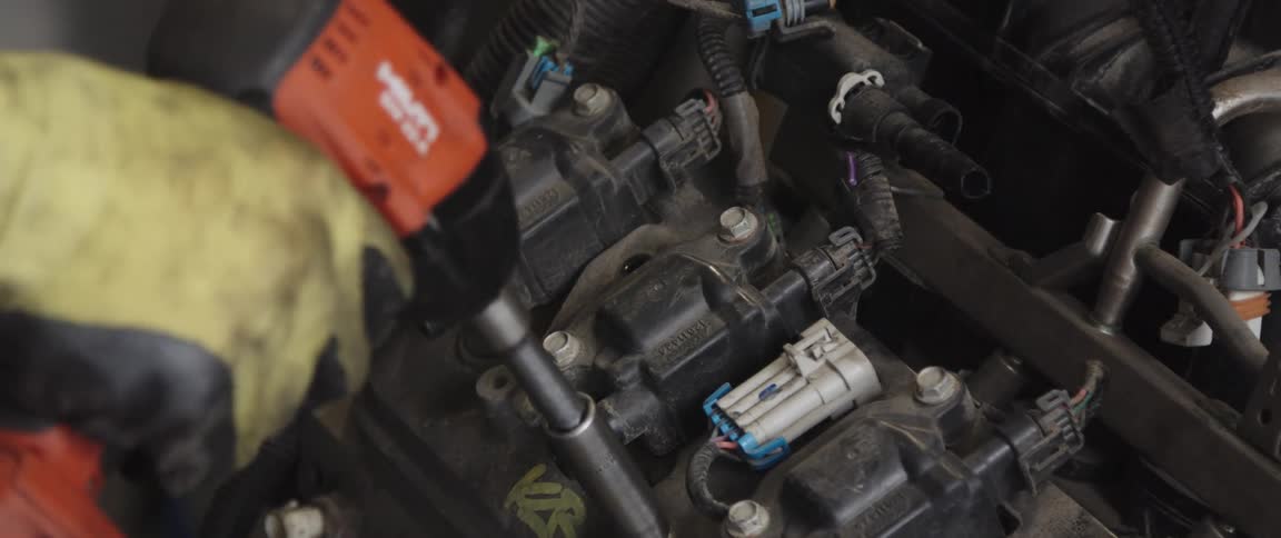 A mechanic removes a bolt in an engine