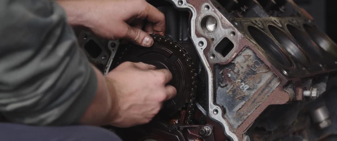 One person oils chain as man attaches disk and chain to engine