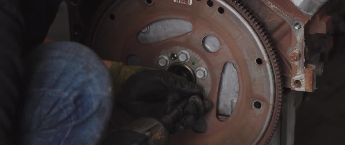 A man uses a hand drill to tighten screws on a machine