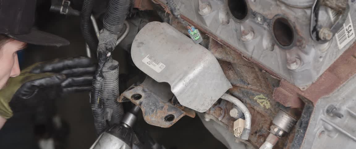 A man is using a drill and working on a car part