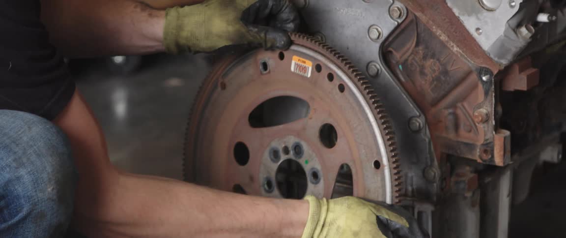 Mechanic with black t shirt jeans and gloves disassembles car engine at the garage