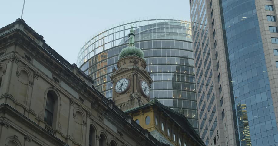 A clock tower surrounded by tall buildings in a metropolis during the day