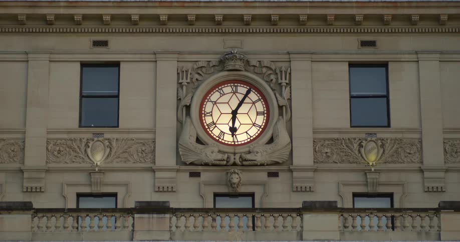 Analog backlit clock on the side of a classic building
