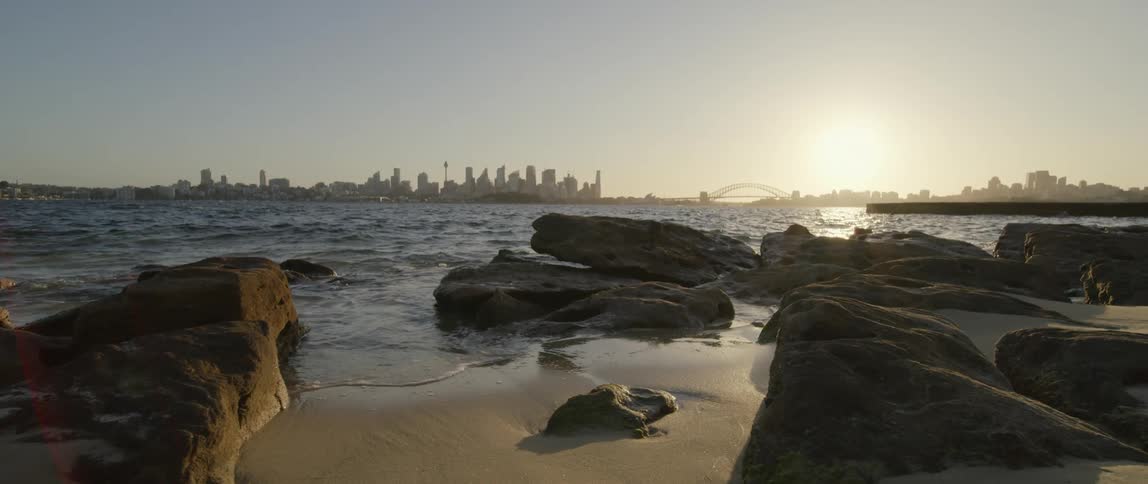 A quiet beach sits across the ocean from downtown
