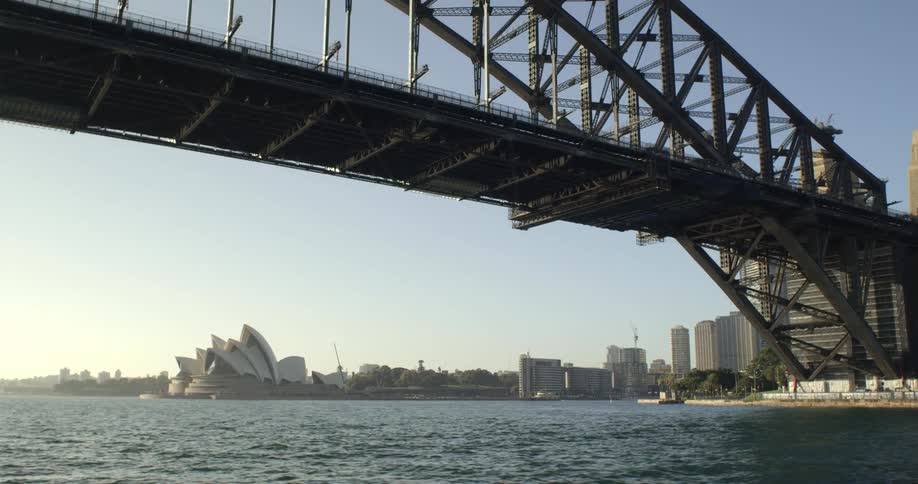The sydney opera house is visible from underneath the sydney harbour bridge