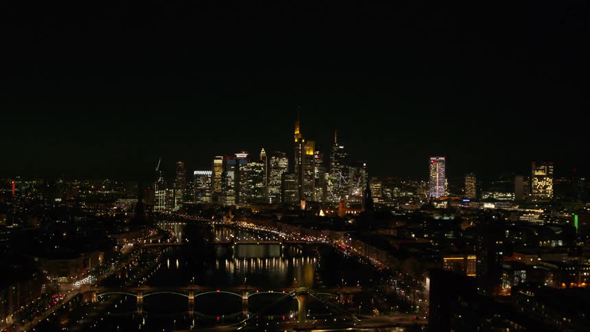 An aerial view of skyscrapers glowing in a large city at night