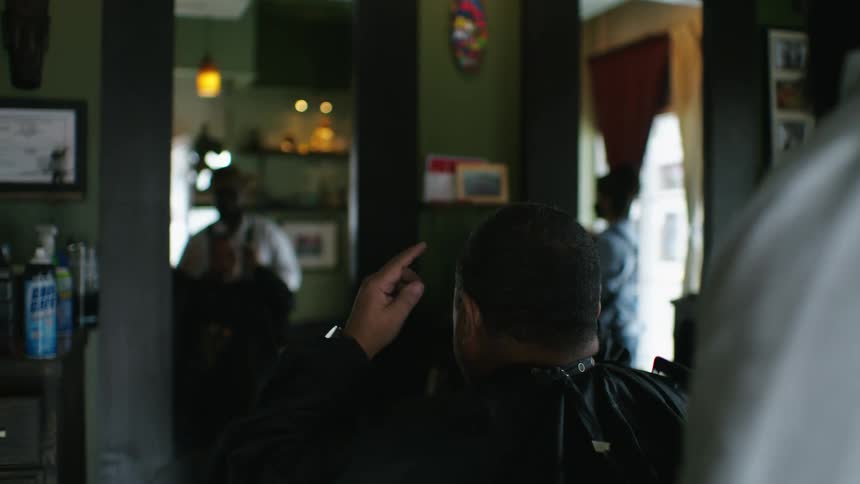 A man is in a barber shop and getting a haircut