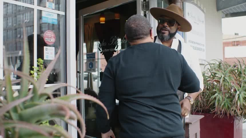 Barber greeting a client at the door of the barber shop with a hug