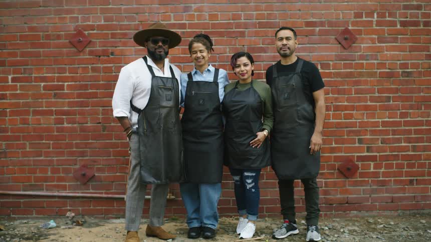 Four coworkers are standing outdoors together by a brick wall