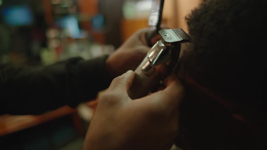 Barber giving a haircut to a client with a hair trimmer inside a barber shop