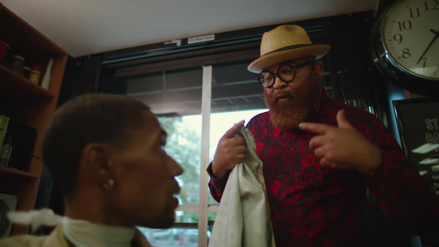 A barber talks to his customer in the chair