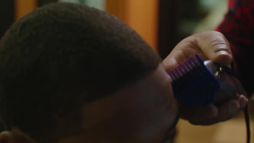 A hairstylist is cutting a clients hair in a barber shop
