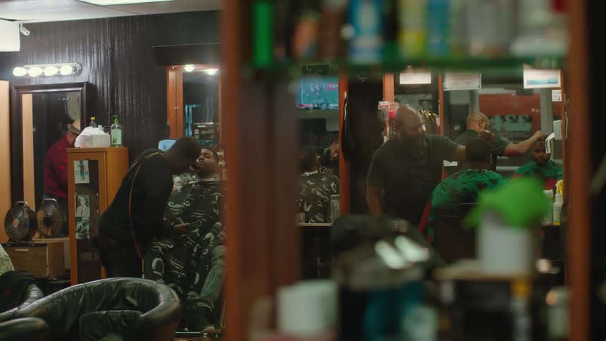 Two men are getting haircuts in a barber shop