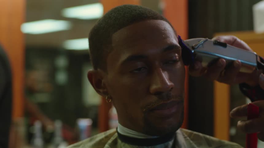 A barber uses clippers to cut a mans hair