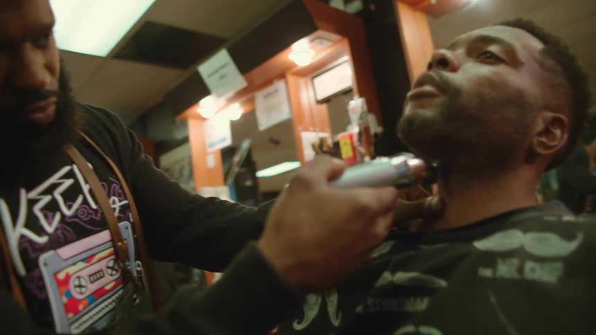 A man is getting his beard trimmed in a barber shop