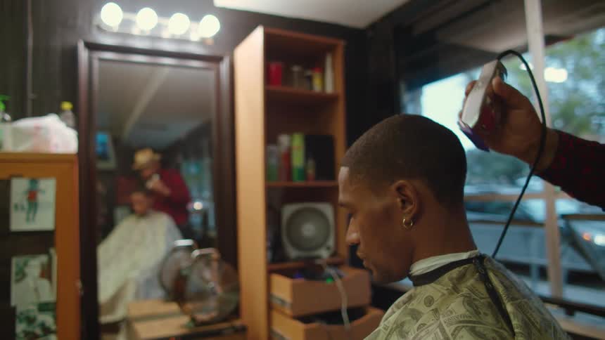 Barber cuts and trims mans hair using clipper in barber shop