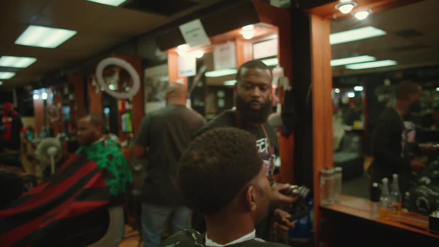 A male barber uses clippers to cut a mans hair