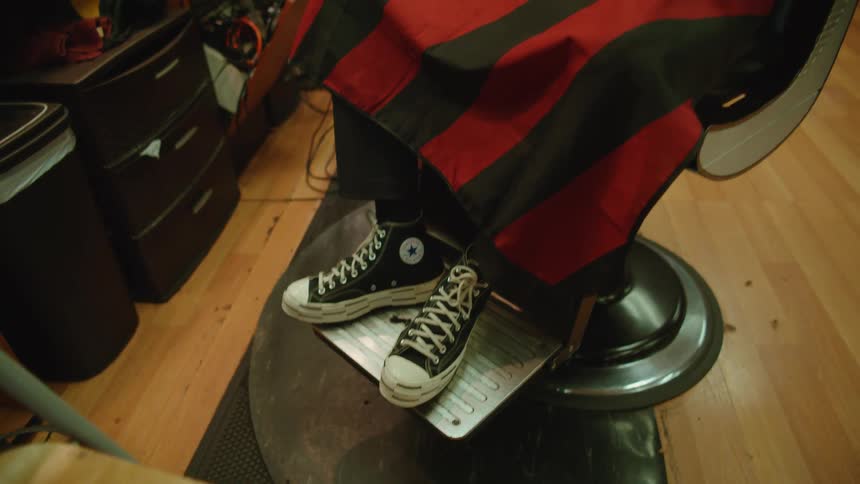 Shoes of a client sitting on a barber shop chair getting his beard shaved