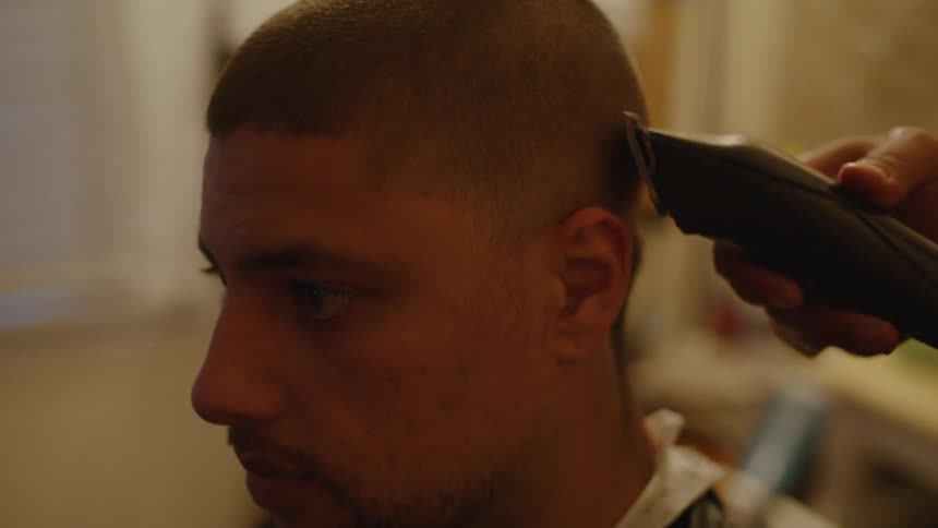 A male barber trimming a mans hair in a barbershop