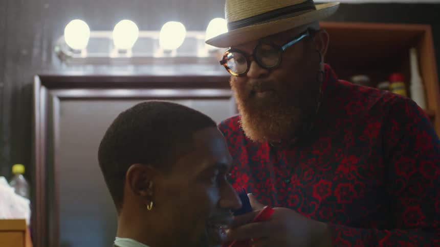 A man sits still as a barber trims his hair
