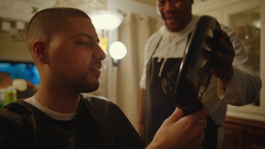 Hairstylist hands client hand mirror to allow them to check the cut