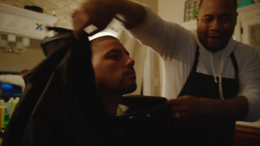 A man is sitting in a barber shop with an employee