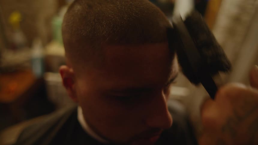 Barber cuts and trims mans hair using clipper in barber shop