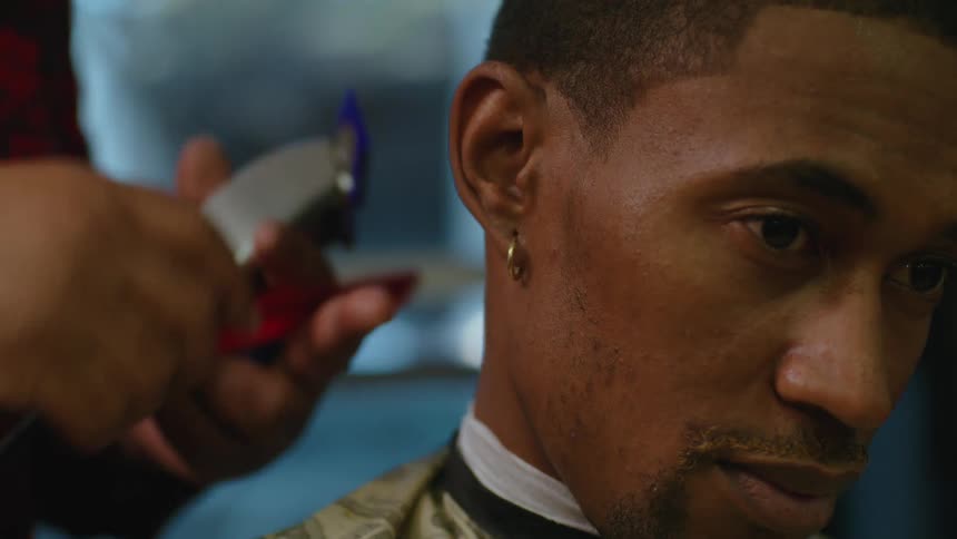 A barber talks while cutting a customers hair with a comb and hair clippers