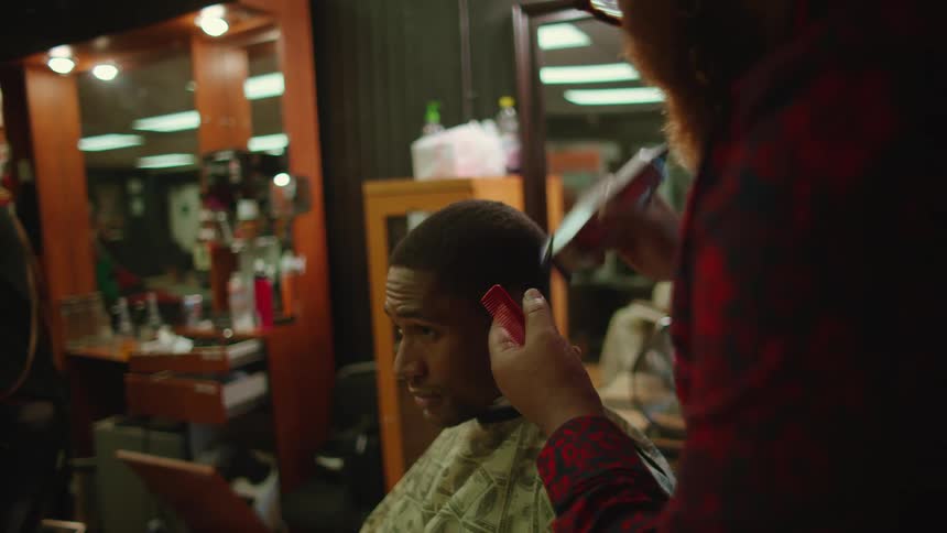 A customer talks to his barber while getting his hair cut in a barber shop